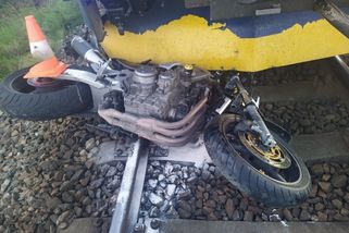 Motorkář předjížděl kolonu čekající před železničním přejezdem. Stroj položil na zem a naboural do další motorky i do vlaku